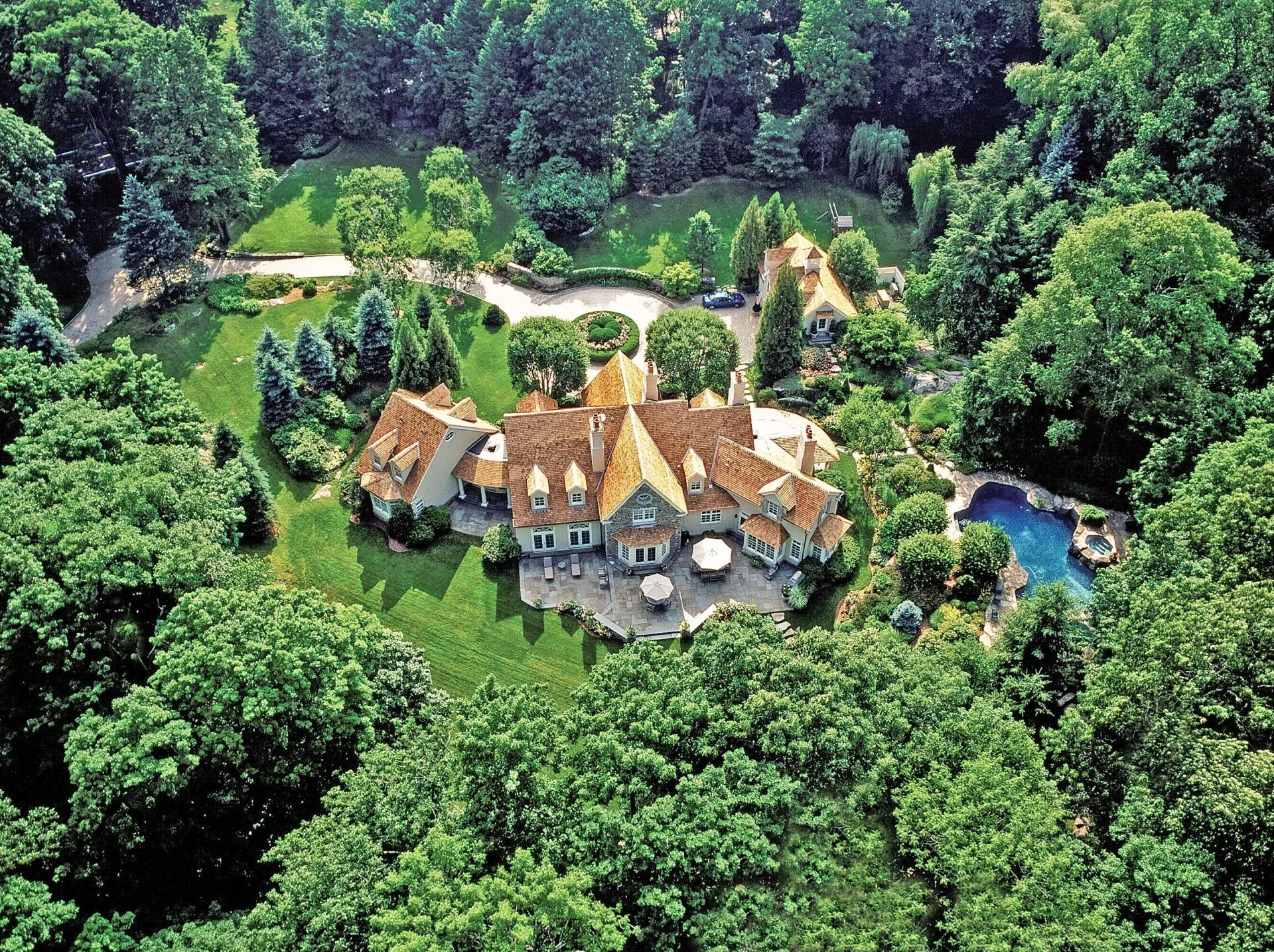Wide aerial view of a finished residential roof and wooded property