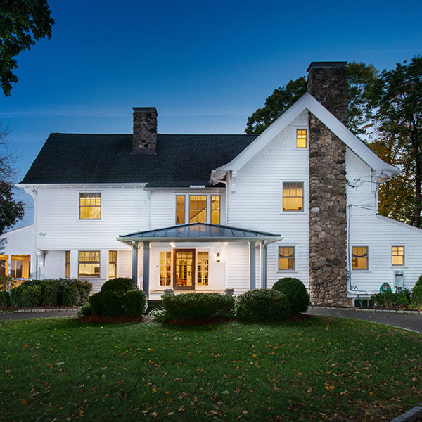 White remodeled residence with a steep dark roof and stone chimney