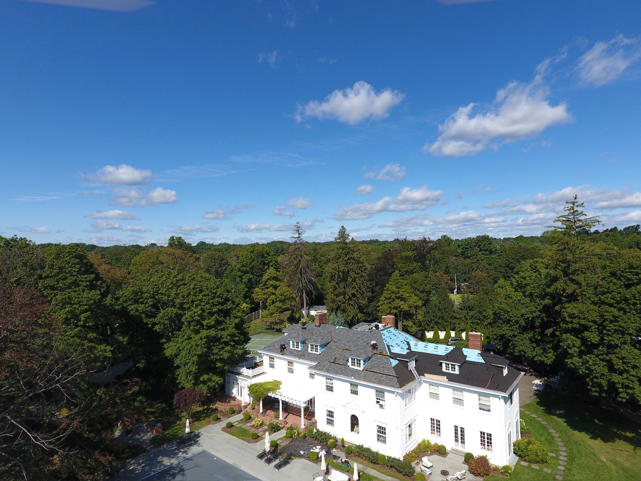Drone view of roof replacement work across a large home's roofline